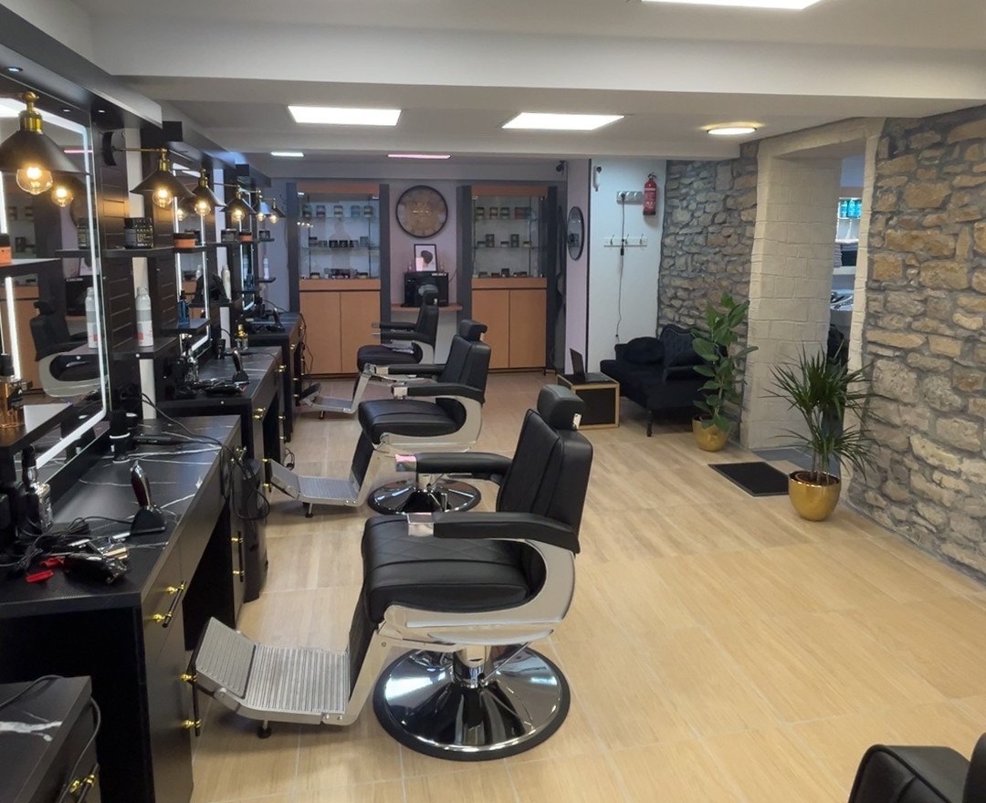 Salle principale du salon : rangée de fauteuils de barbier face au mur en pierre