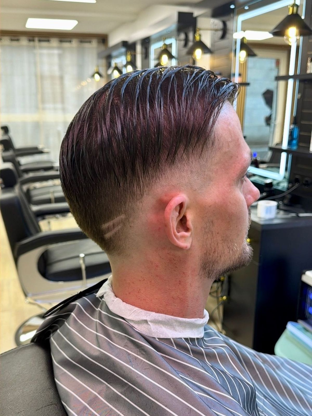 Dégradé avec motif rasé et coiffé en arrière — réalisation Richi Coiffure